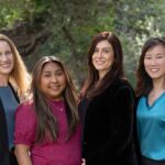 The Gold Law paralegals and support staff standing together outdoors among green trees