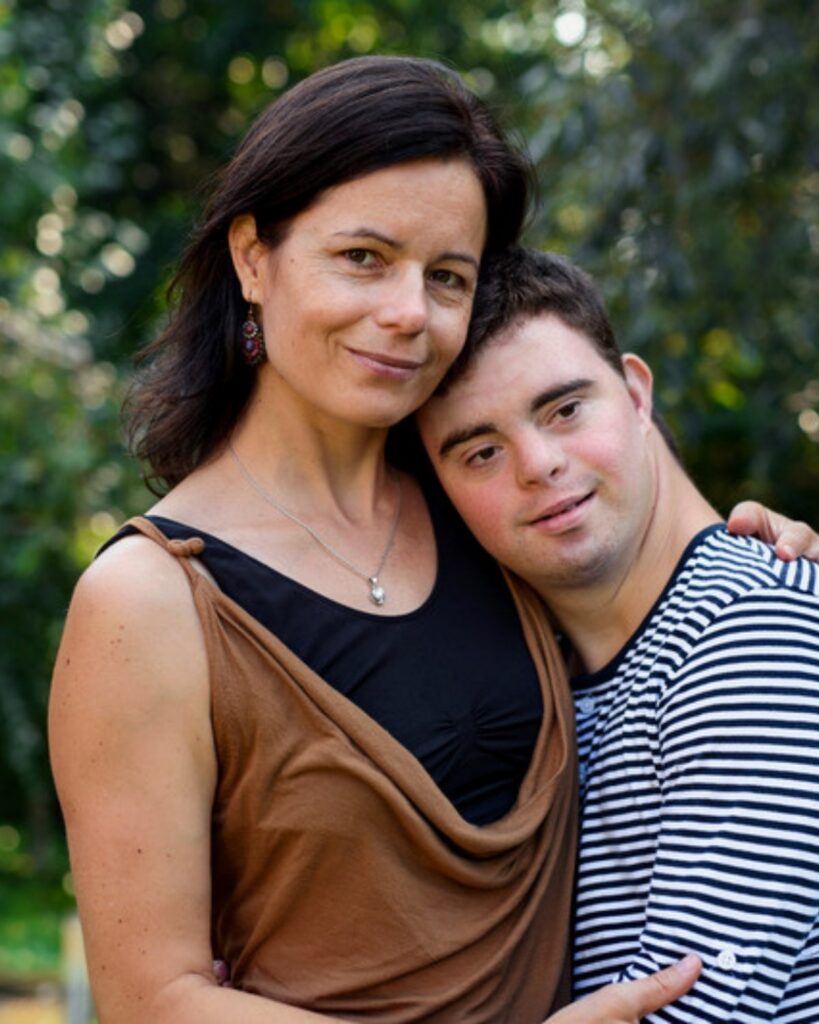 A mother with her arm around her adult son who has Down syndrome