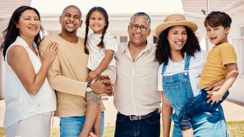 Three generations of a family standing together on the lawn outside their home