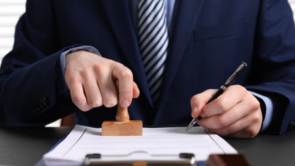 A notary pressing a stamp onto a signed document