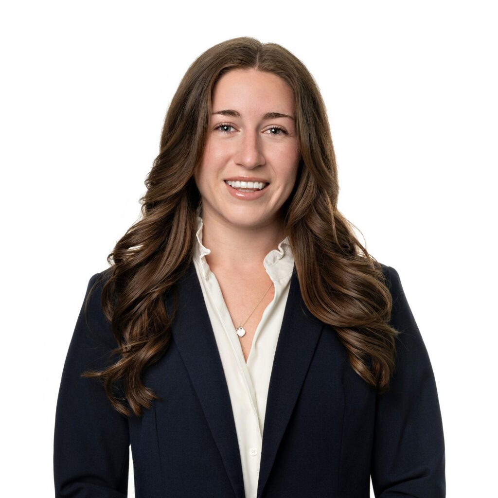 Estate planning attorney Megan Lee smiling in a navy suit jacket and open collared white shirt