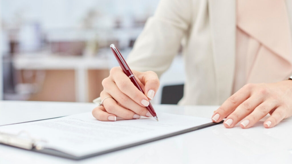 A woman signing a beneficiary form reviewed by an estate planning lawyer in Port Hueneme
