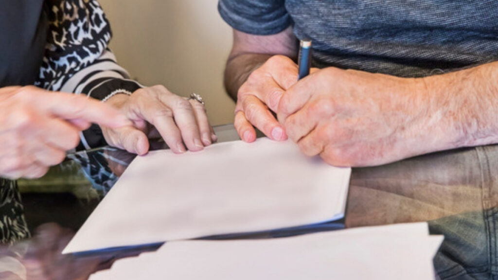 An older man signing a deed reviewed by an estate planning lawyer in Thousand Oaks