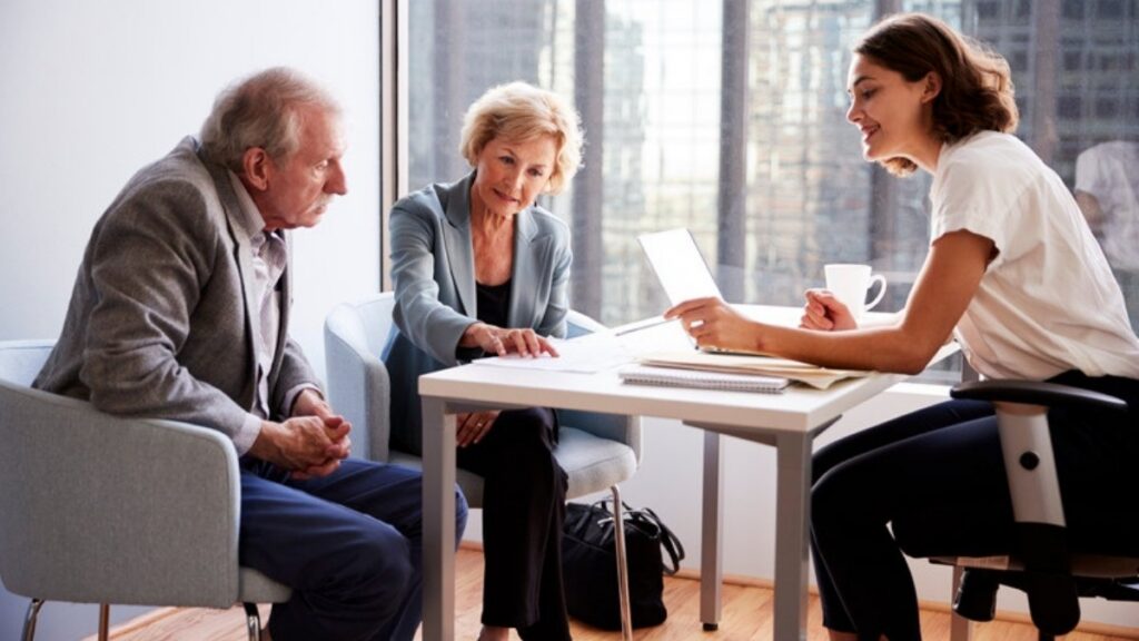 An older couple talking through their plan with an adviser across a small office table