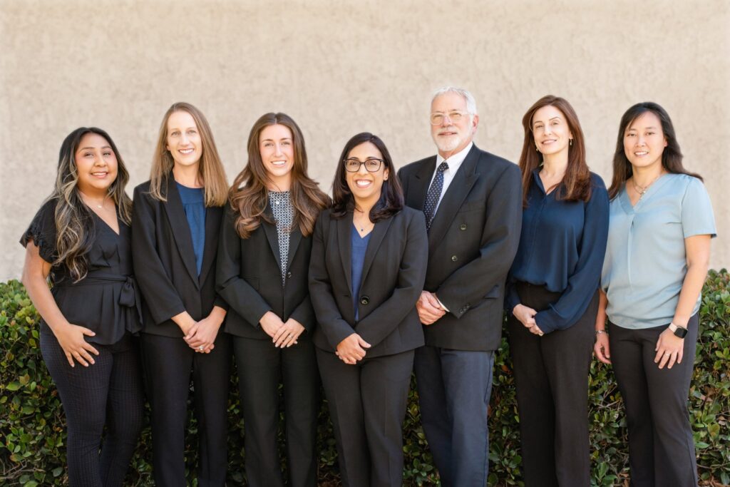 The attorneys and staff of Gold Law, a Camarillo estate planning law firm, standing together in front of a hedge